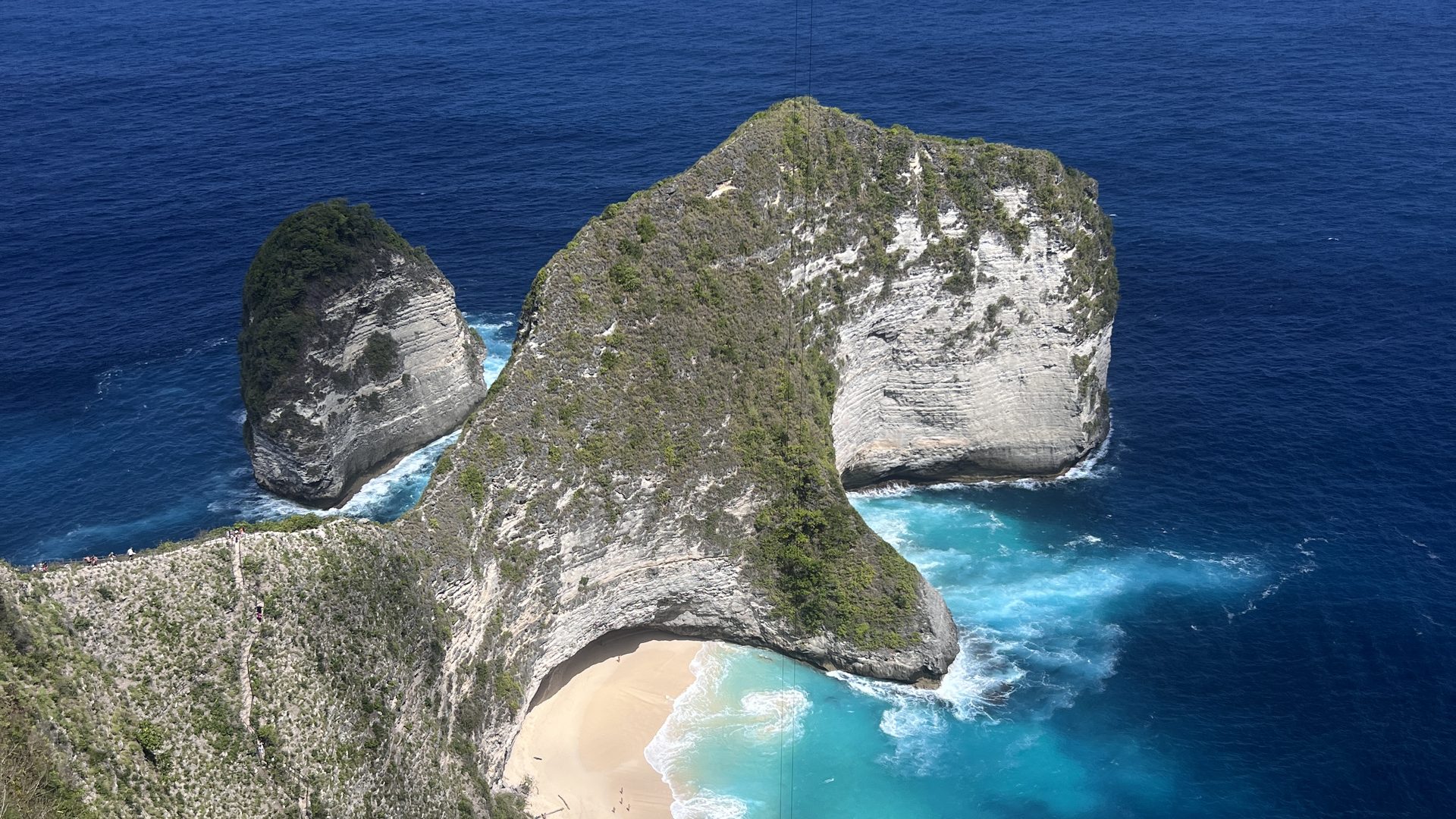 峇里島佩妮達島精靈墜崖 Kelingking Beach，恐龍形狀的綠色懸崖伸入湛藍印度洋，崖下是一彎白沙灣